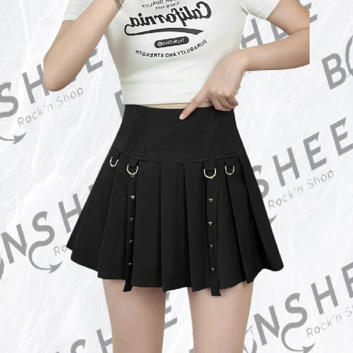 Mini-jupe plissée noire portée de style gothique avec anneaux métalliques à la taille et rivets cœurs.
